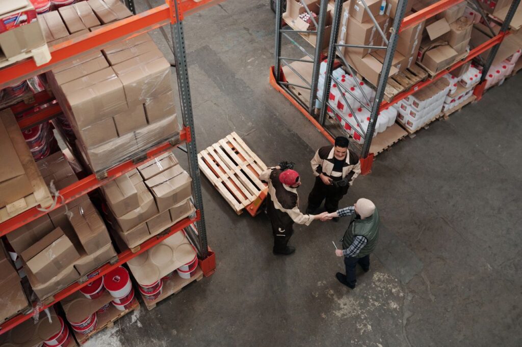 High angle view of workers shaking hands in a warehouse, symbolizing teamwork and logistics.